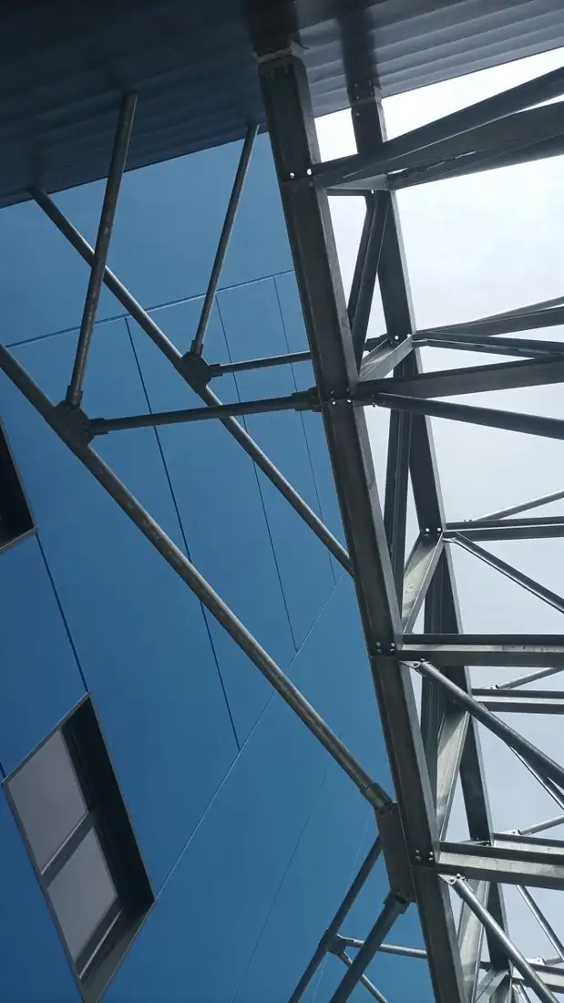 Struttura reticolare in acciaio zincato vista dal basso contro la facciata blu