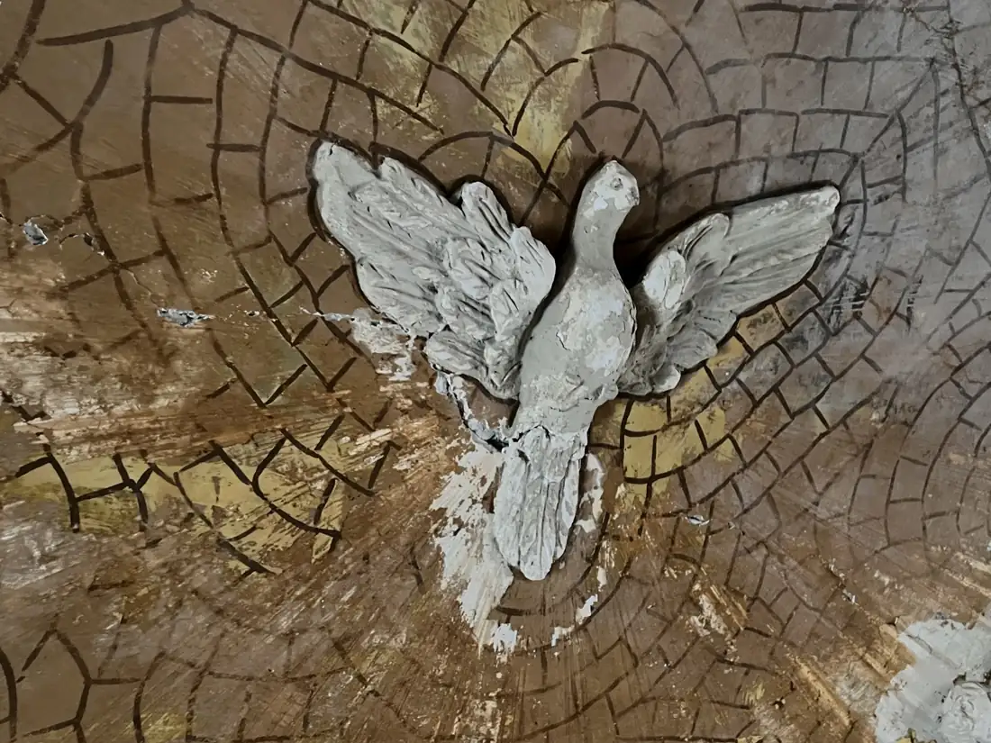 Prima del restauro: colomba in stucco su un fondo ridipinto a riquadri scuri, con lacune e distacchi