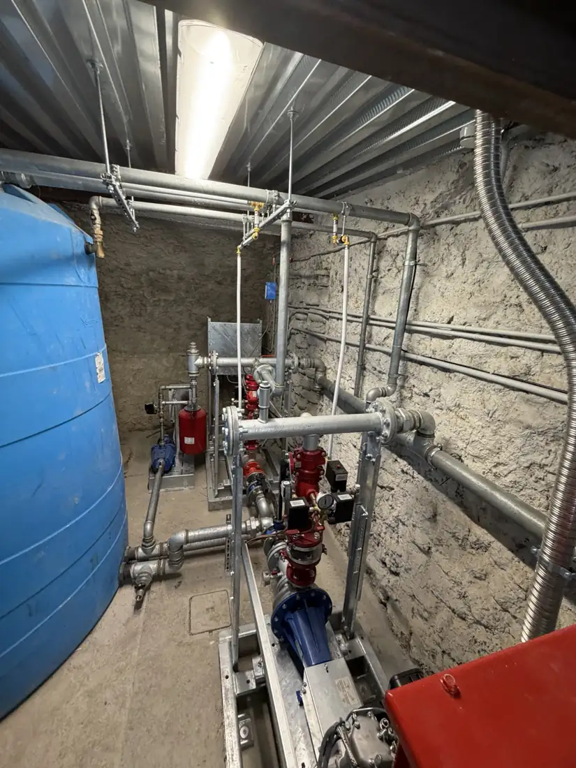 Locale tecnico con la centrale idrica antincendio: serbatoio di accumulo, gruppo di pompaggio, valvole e tubazioni in acciaio zincato